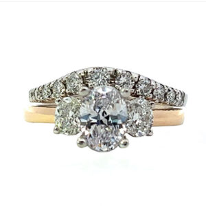 Two tone yellow and white gold 3 stone engagement ring set with two oval side diamonds .45ct tw and matching French prong brilliant cut diamond wedding band .35ct tw